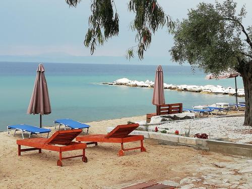 斯卡拉索提罗斯Marti Resort的海滩上的一组椅子和遮阳伞