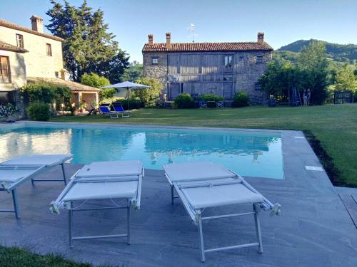 卡尔佩尼亚Country House "Locanda Le Querce"的一座房子旁的游泳池,配有两把躺椅