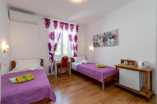 尼亚卢卡Marica Guesthouse的一间卧室配有两张带紫色床单和一张桌子的床。