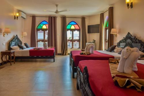 桑给巴尔Tembo Palace Hotel的一间带三张床的卧室和彩色玻璃窗