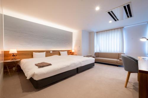 HukueSERENDIP HOTEL GOTO的卧室配有一张白色的大床和一张沙发。