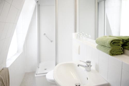 巴特基辛根诺德兰别墅旅馆的白色的浴室设有水槽和淋浴。
