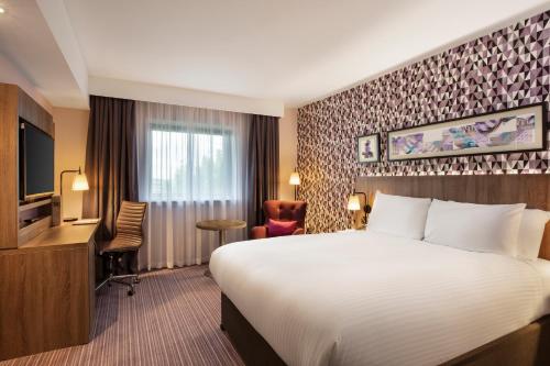 希灵登Leonardo London Heathrow Airport的酒店客房设有一张大床和一张书桌。