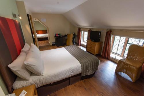 彼索普斯托福传统大哈林勃利庄园酒店的一间卧室配有一张床、一台电视和一把椅子