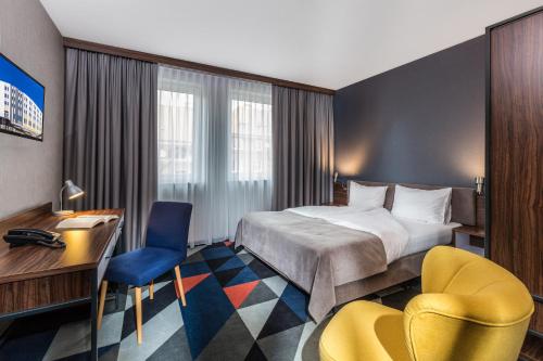 什切青伏尔甘酒店的酒店客房,配有一张床、一张桌子和椅子