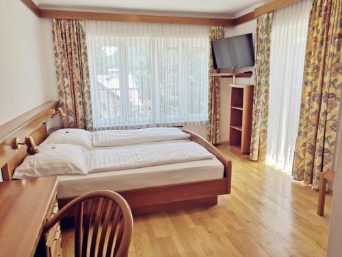 圣卡尼兹Hotel Auszeit的一间卧室配有一张床、一张桌子和一个窗户。
