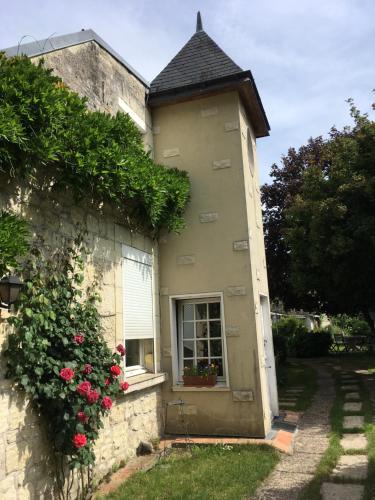 Avoinechambre sur jardin entre Fontevraud et RignyUssé的一座有窗户和玫瑰树丛的建筑