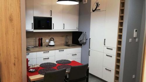 华沙Apartament Bielany Oczapowskiego的一间小厨房,配有红色的桌子和白色的橱柜