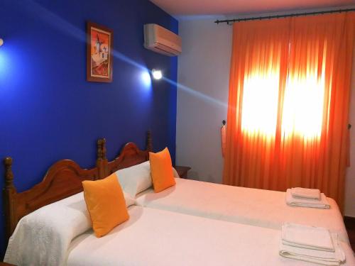 坎波德克里普塔纳Hostal Restaurante Ego's的一间卧室配有一张大床,拥有蓝色的墙壁和橙色的窗帘