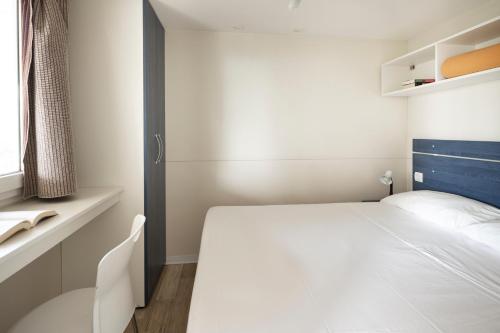 博格利斯科Camping Genova Est的卧室配有白色的床和窗户。