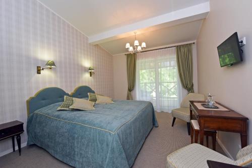 比尔什托纳斯经典别墅旅馆的酒店客房配有蓝色的床和电视。