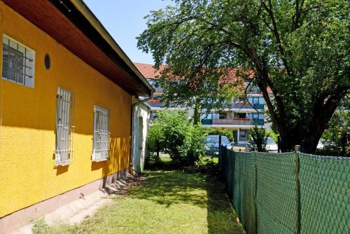 阿舍尔斯莱本Ferienwohnung/ Ferienzimmer Asche的树旁有栅栏的黄色建筑