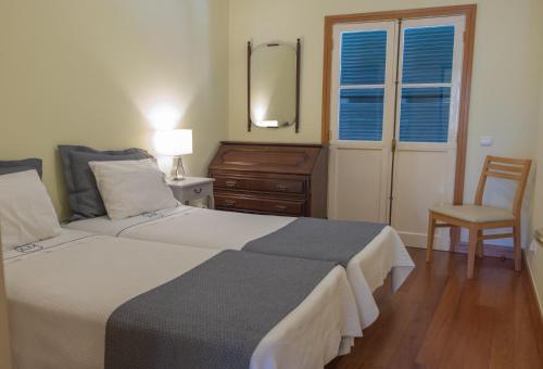 丰沙尔马德拉圣玛丽亚公寓的一间卧室配有两张床、一把椅子和镜子