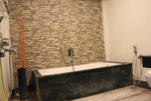 尼尔岛Tango Beach Resort的带浴缸的浴室和砖墙