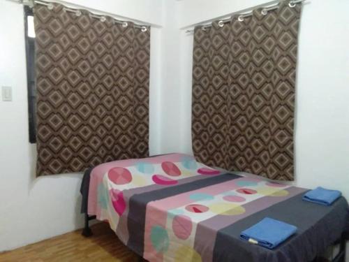 马尼拉马卡蒂经济一室公寓的小卧室配有一张带彩色床罩的床