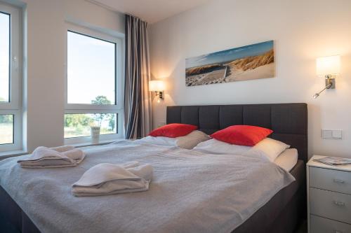加兹尤瑟多姆Appartement "Saphir" mit Penthouseflair - Oase am Haff的一间卧室配有一张大床和红色枕头