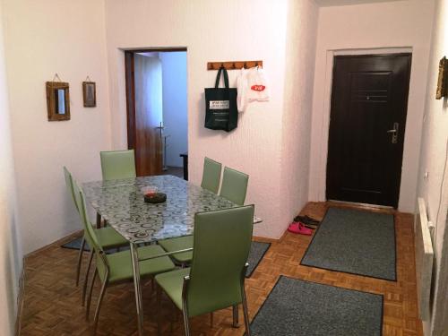 尼什Niš Apartman的一间带桌子和绿色椅子的用餐室