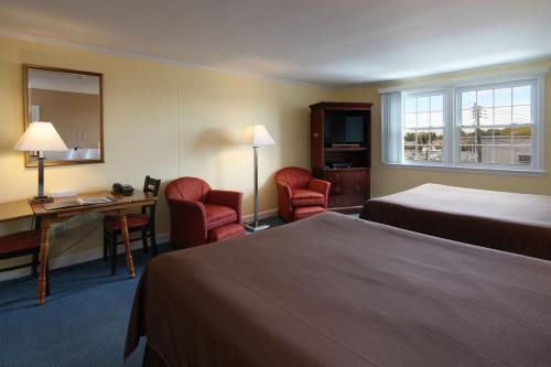 海恩尼斯科德角港大厦酒店的酒店客房带两张床、一张桌子和椅子。