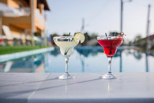 圣佐治欧斯帕贡San Georgio Boutique Hotel by Hotelius的坐在泳池旁的桌子上,三杯鸡尾酒