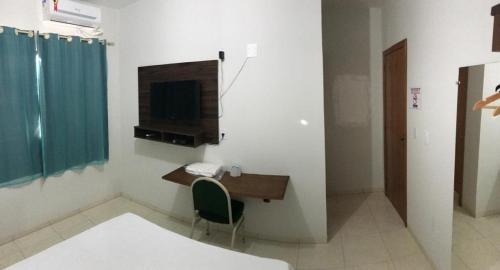 Campo VerdeBRAVO CITY HOTEL CAMPO VERDE的一间房间,配有一张桌子和一台墙上的电视