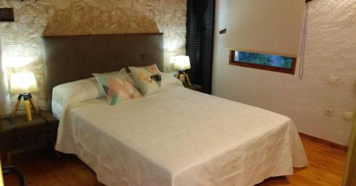 贝塞特La Pedrera的一间卧室配有一张带两盏灯的大型白色床。