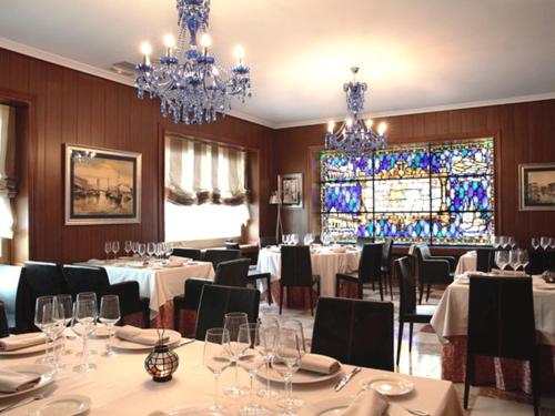 布里维耶斯卡Hosteria El Valles 2 ESTRELLAS的用餐室配有桌椅和彩色玻璃窗