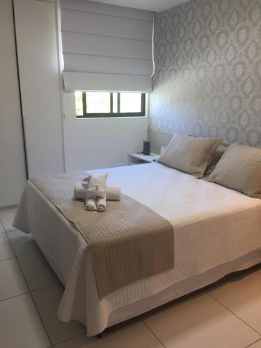 拉巴拉德纳圣米格尔Apto Luxo Iloa Barra de São Miguel的卧室配有一张白色大床,上面有一只动物填充物