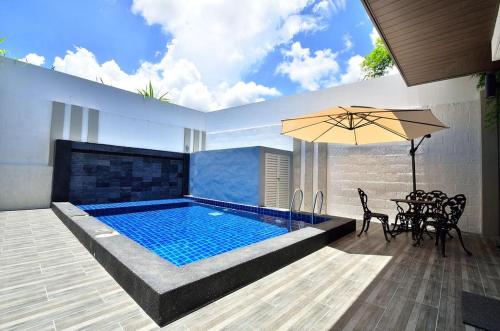 峇都丁宜紫罗兰奢华服务别墅的一个带桌椅和遮阳伞的游泳池