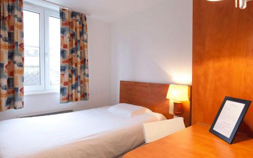 斯特拉斯堡21世纪酒店的一间卧室配有一张床、一张书桌和一个窗户。