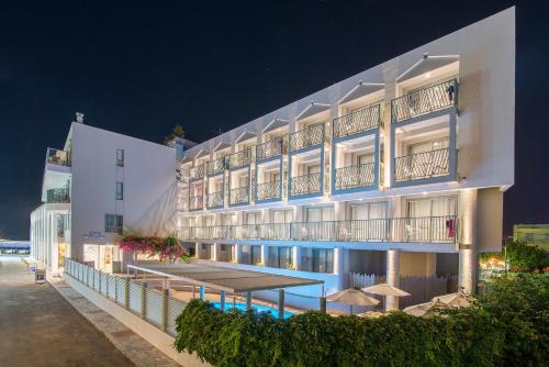 赫索尼索斯Alia Beach Hotel by Estia的大型白色酒店,晚上设有游泳池
