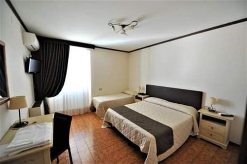 巴斯蒂亚乌姆布拉Hotel Il Cammino Di Francesco的酒店客房配有两张床和一张书桌