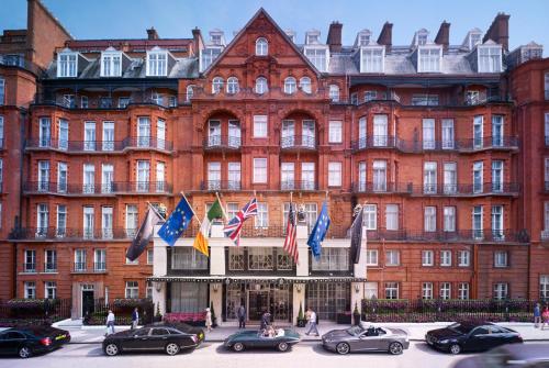 伦敦梅宝尼克拉里奇酒店的一座大型红砖建筑,前面有汽车停放