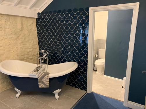 BinegarThe Mendip Inn的蓝色的浴室设有浴缸和卫生间。