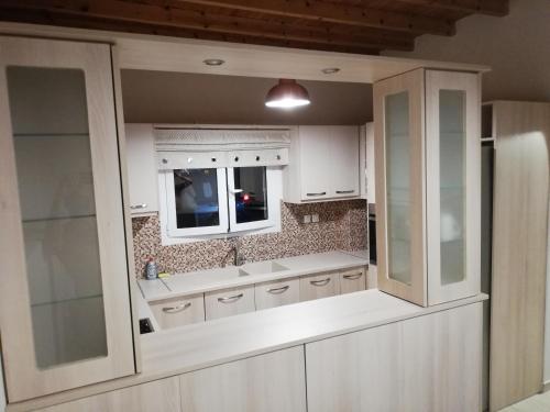 阿达玛斯Iremia Rooms的厨房配有白色橱柜、水槽和窗户。