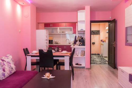 瓦尔纳Apartment Nicole的一间带桌子的客厅和一间带粉红色墙壁的厨房