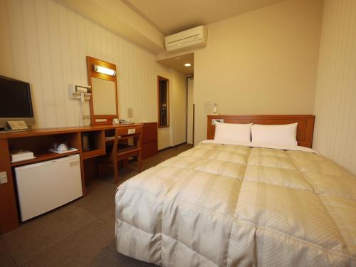 佐贺市佐贺站前干线酒店的一间卧室配有一张床、一张书桌和一台电视