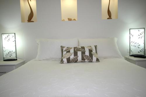 莫里莫科Mollymook Beach Waterfront的卧室配有带两盏灯的白色床