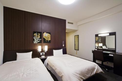 苫小牧市苫小牧站前旅馆的酒店客房设有两张床、一张桌子和一面镜子
