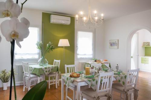 Piombino DeseLa Casa di Amedeo的一间拥有绿色墙壁和白色桌椅的用餐室