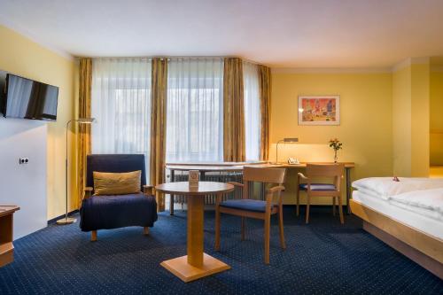 卡尔斯鲁厄acora Karlsruhe Zentrum Living the City的酒店客房带一张床、一张桌子和椅子
