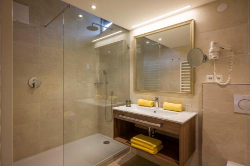 蒂罗尔州圣约翰乡间美景旅馆的一间带水槽、淋浴和镜子的浴室