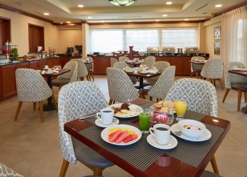 圣萨尔瓦多Suites las Palmas, Hotel & Apartments.的用餐室配有桌椅和食物