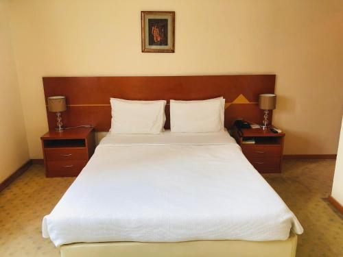 罗安达Golden Park Hotel的一间卧室配有一张带2个床头柜的大型白色床