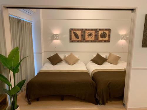 冲绳岛市Allstay CHIBANA的配有镜子的客房内的两张床