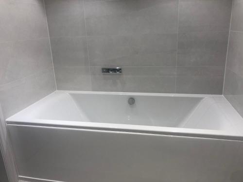 鲁吉利Tuppenhurst Barn的白色瓷砖浴室内的白色浴缸