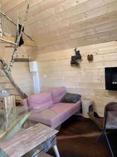 特雷尼Ecolodge Beauregard的客厅配有带紫色沙发的木墙