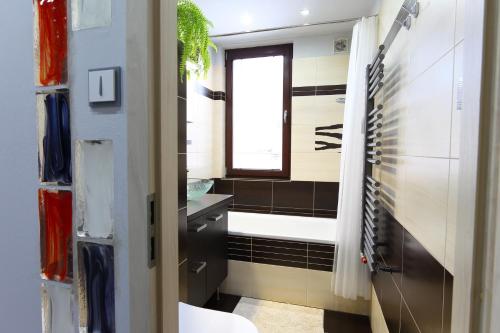 卢捷拿纳德德斯努Apartmán 77的带浴缸、水槽和窗户的浴室