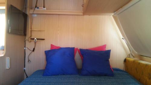 La VeguetaChalet en oasis privado的小房间里一张带蓝色和红色枕头的床