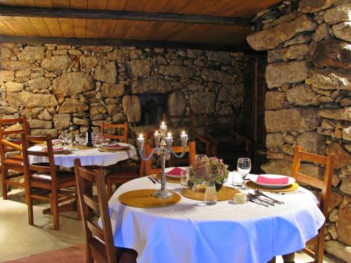 MontezinhoA Lagosta Perdida的一间设有两张桌子和石墙的用餐室