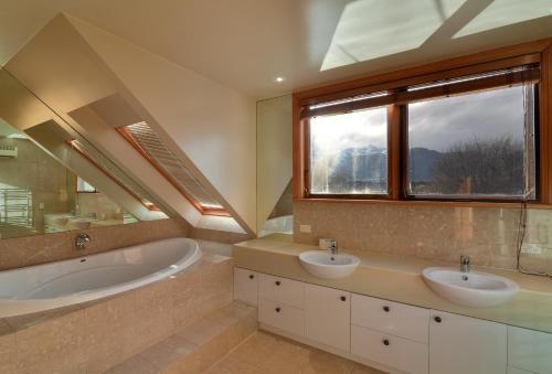 皇后镇Manata Homestead & Lodge的一间带两个盥洗盆、浴缸和窗户的浴室